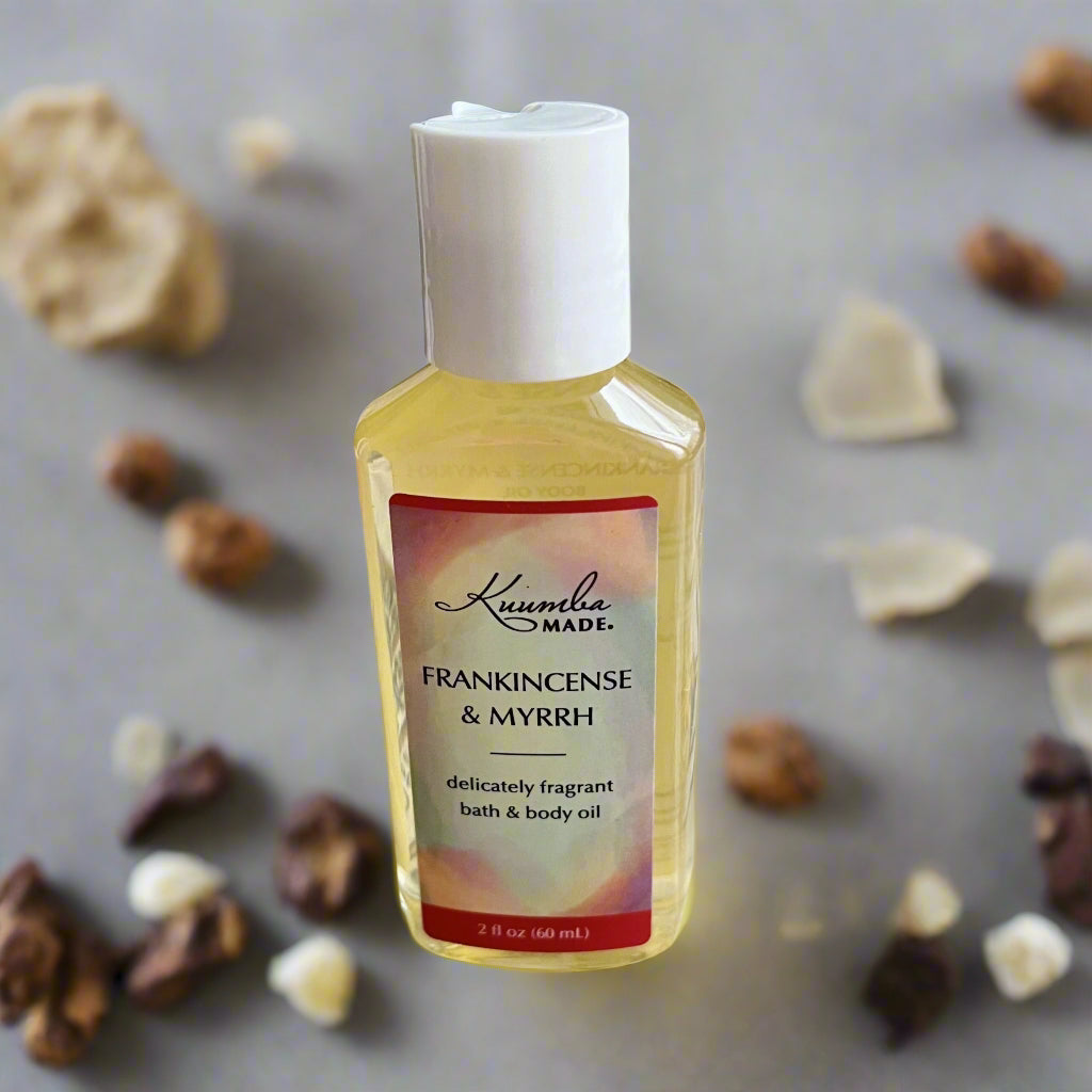 Organinis kūno aliejus su frankincensu ir mira stikliniame buteliuke, šalia žvakės ar meditatyvios erdvės